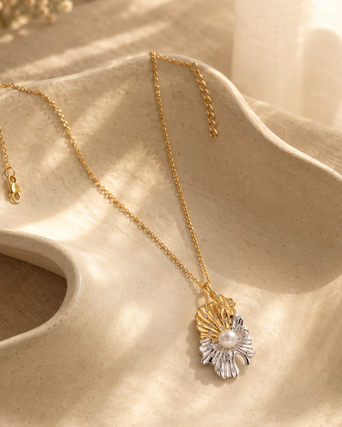 Artisanal dual-tone gold & silver pearl pendant on natural ceramic tray; capturing the brand’s organic, beach-inspired story